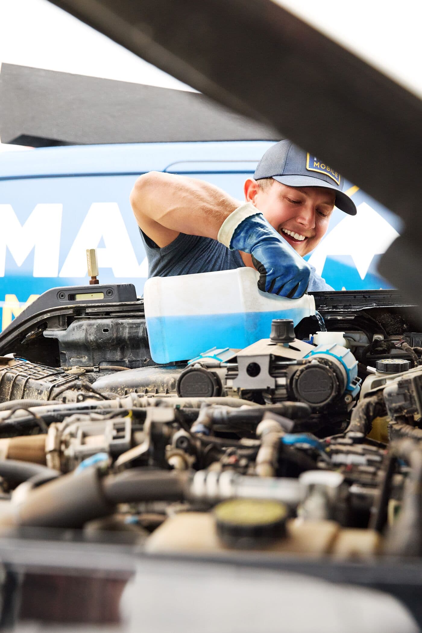 A MAXI technician topping off fluids under the hood