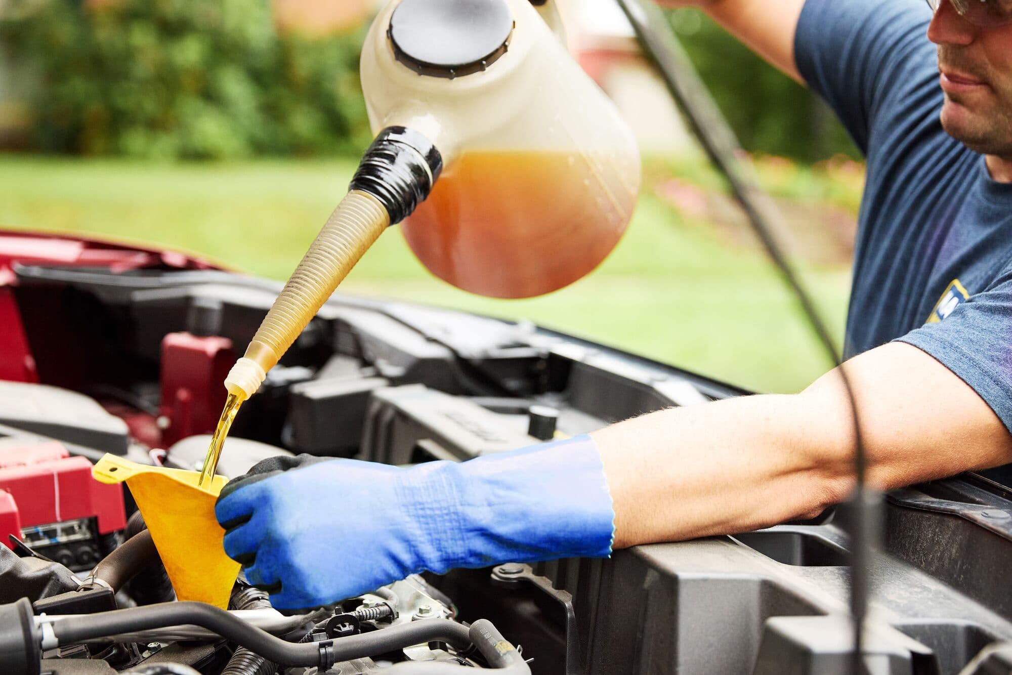 A MAXI technician pouring full-synthetic oil through a funnel