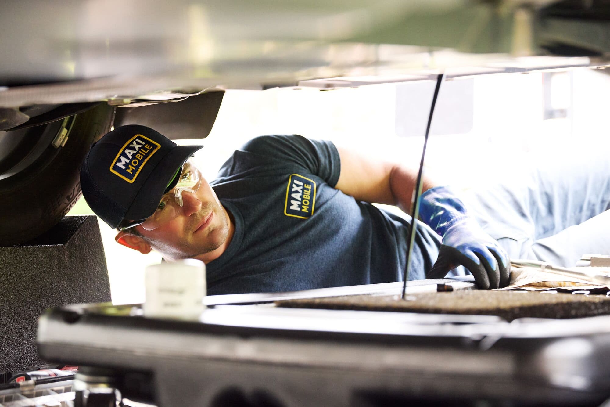 A MAXI Mobile technician working under the hood during a service