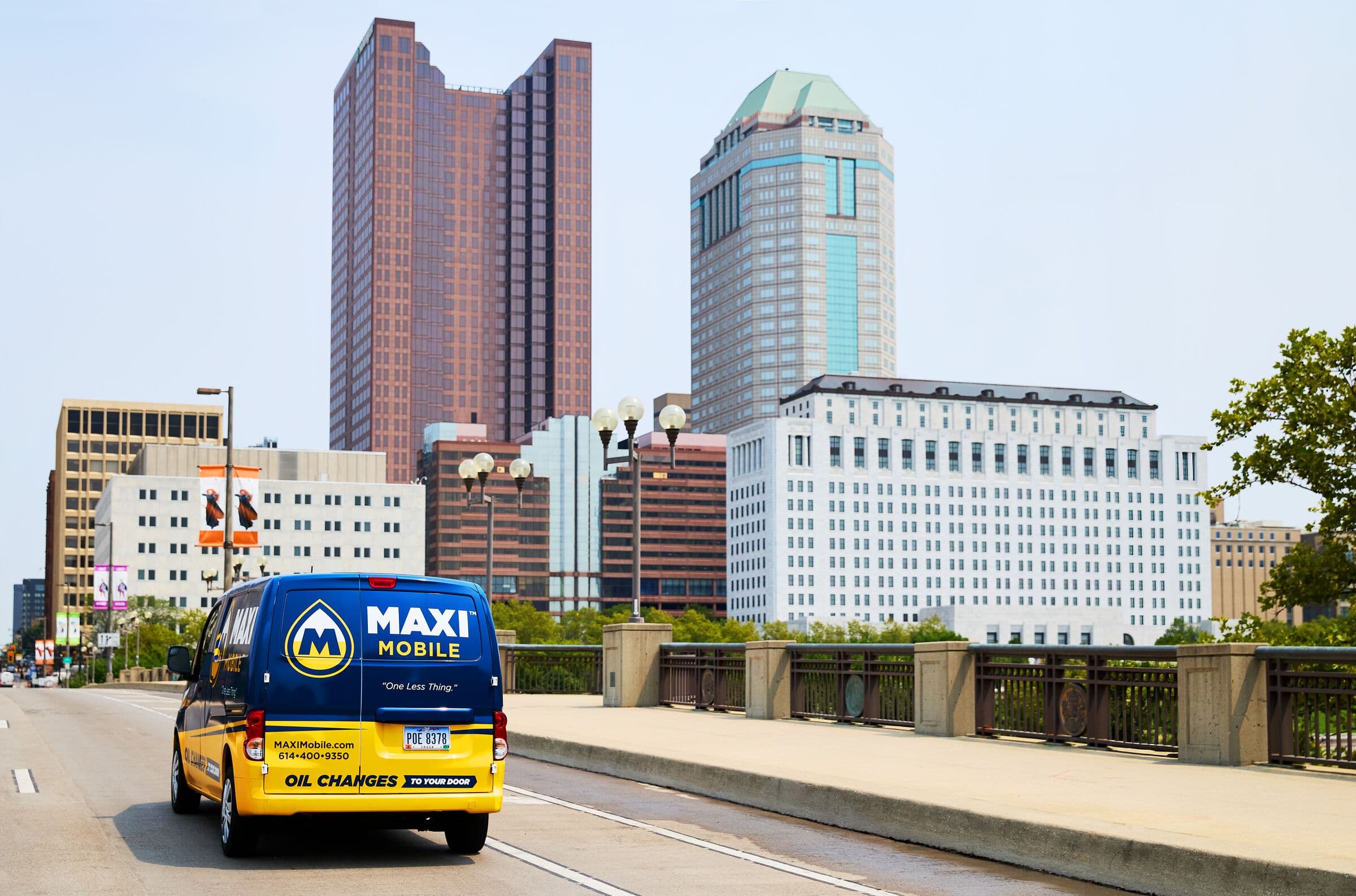 A MAXI Mobile service van driving into downtown Columbus with the skyline behind it
