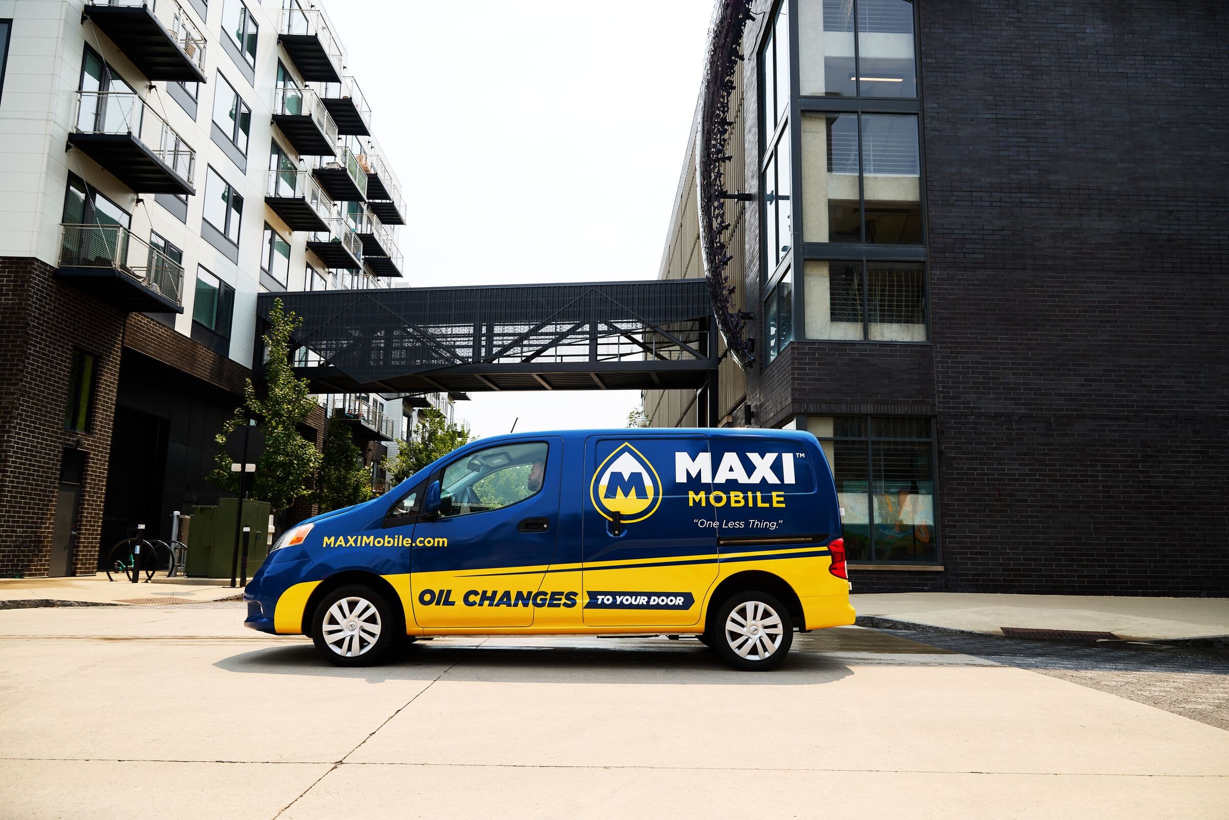 A MAXI Mobile service van parked downtown beneath a skybridge