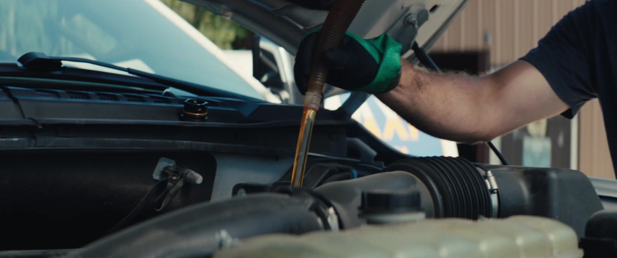 A MAXI Mobile technician pouring full-synthetic oil during a service