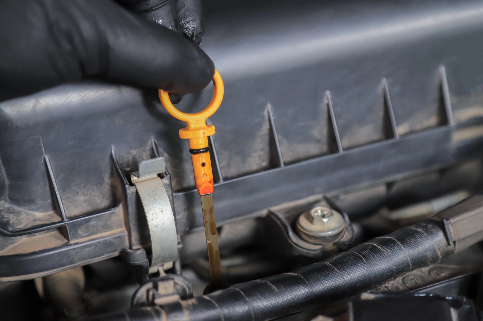 Technician pulling the oil dipstick to inspect oil condition